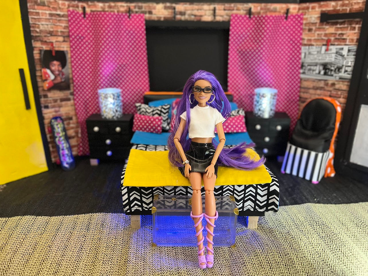 Barbie doll with purple hair sitting on a colorful couch in a room with brick walls and pink curtains.