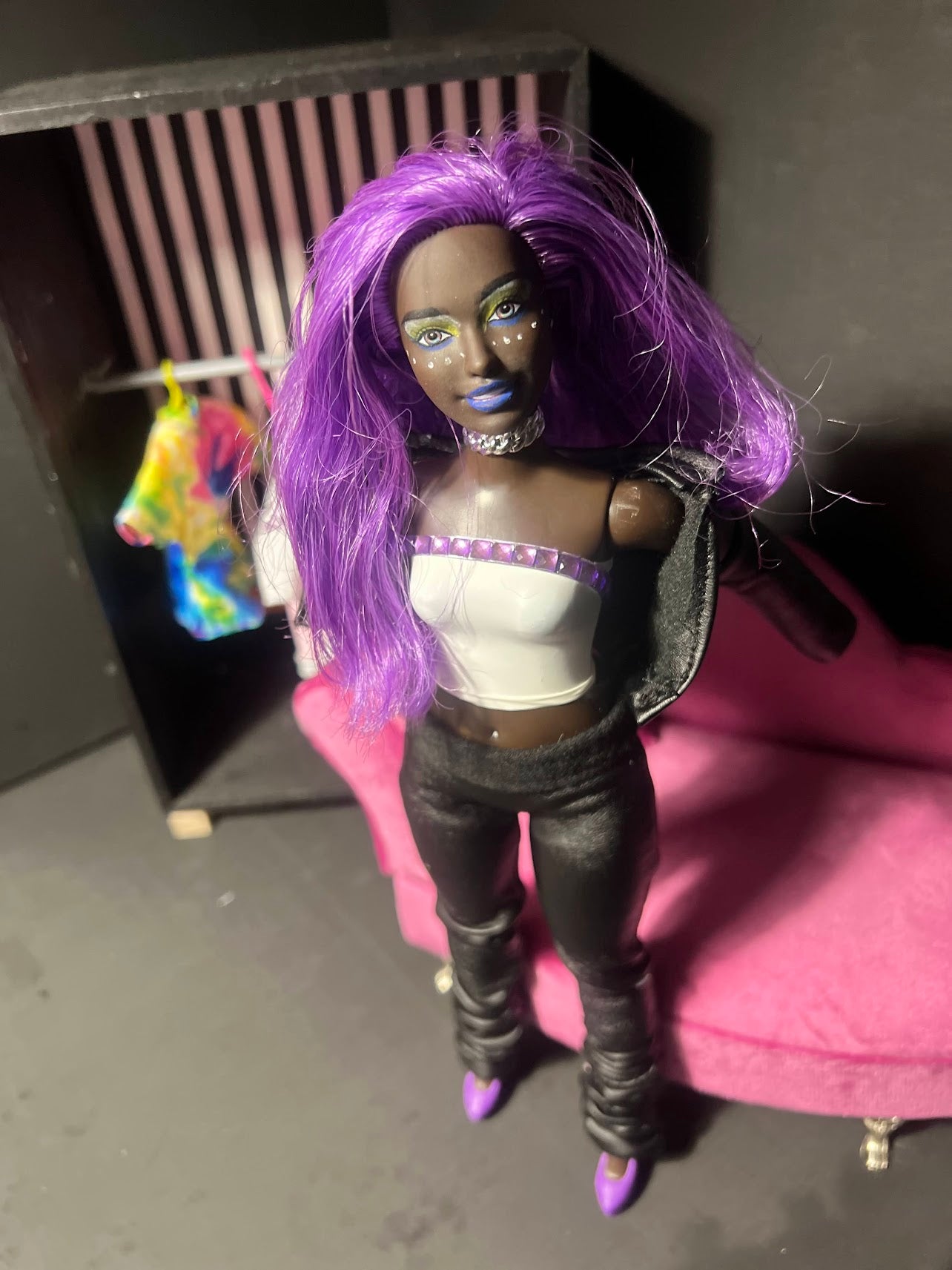 Doll with purple hair and outfit on a dark background